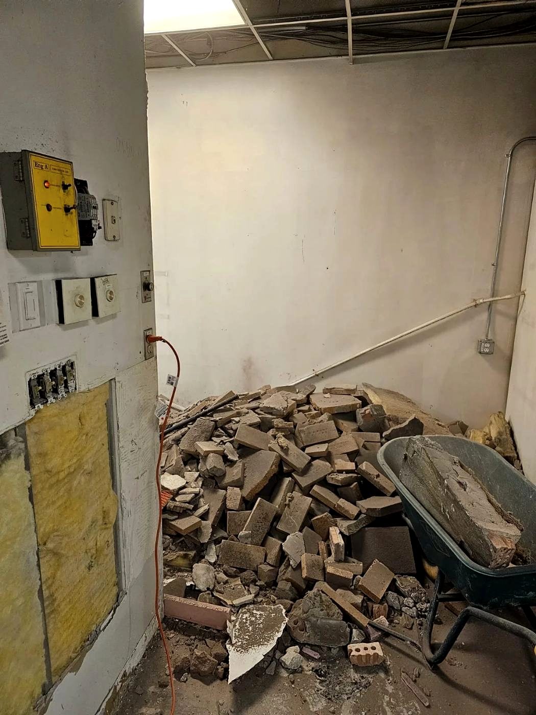 Brick and block debris stacked beside exposed electrical panels