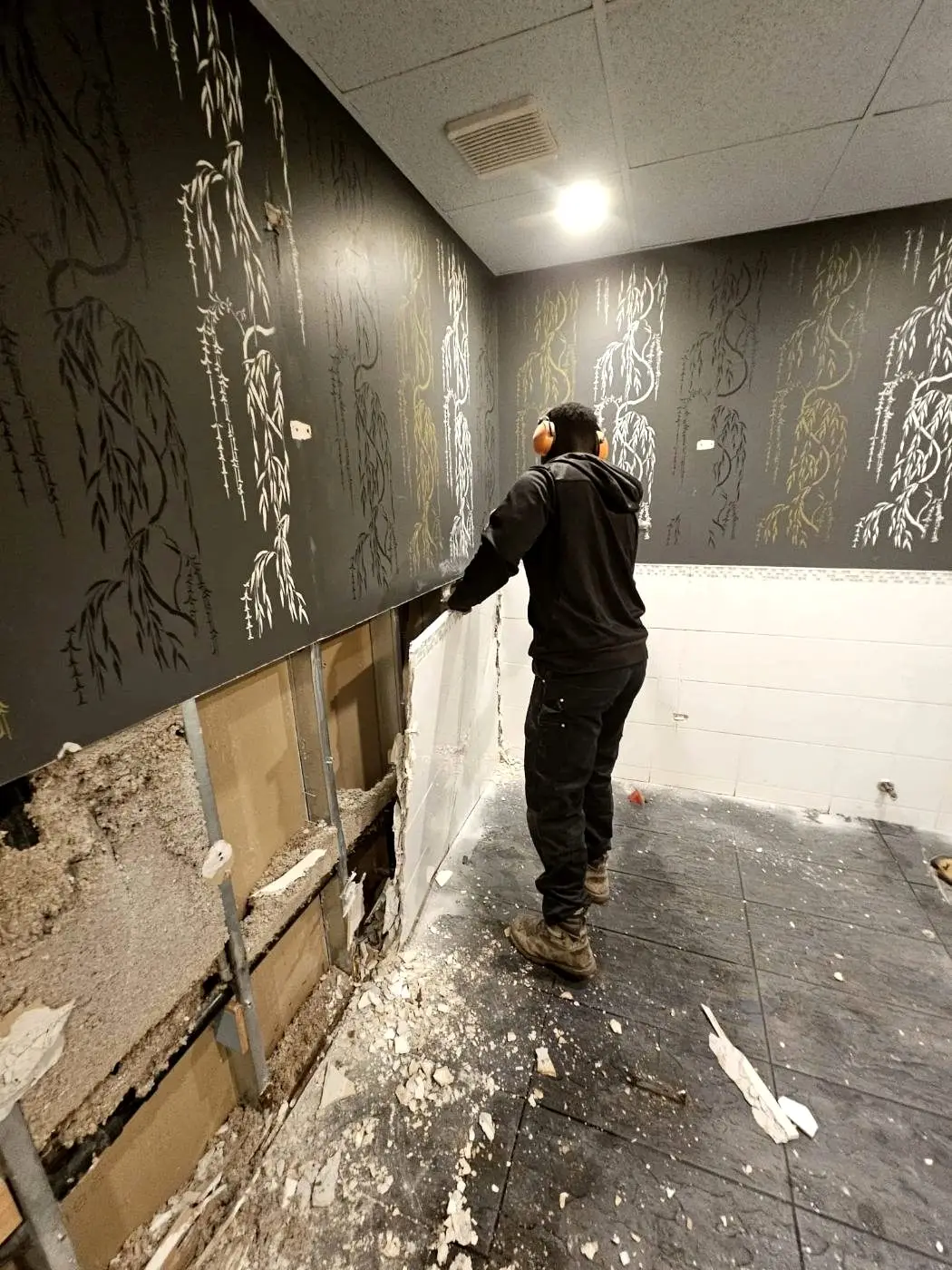 Zebra Demolition crew member stripping out a commercial interior wall